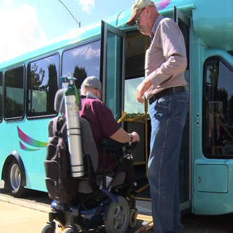 Man in wheelchair being helped onto city bus