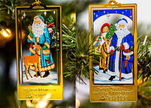 Two ornaments featuring depictions of Santa Claus hang on a tree.