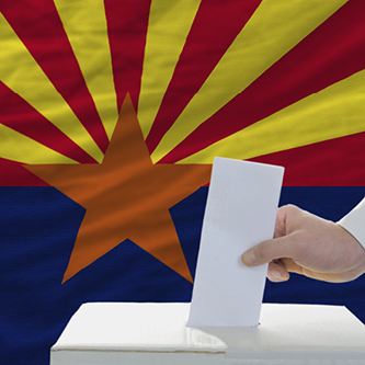 Ballot being placed in a ballot box with the Arizona state flag in the background