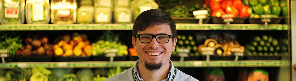 A man standing in front of produce at a grocery store