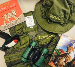 A backpack, hat, pair of binoculars, and children's wildlife books.