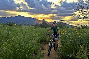 Cyclist riding at sunset with mountains in the background